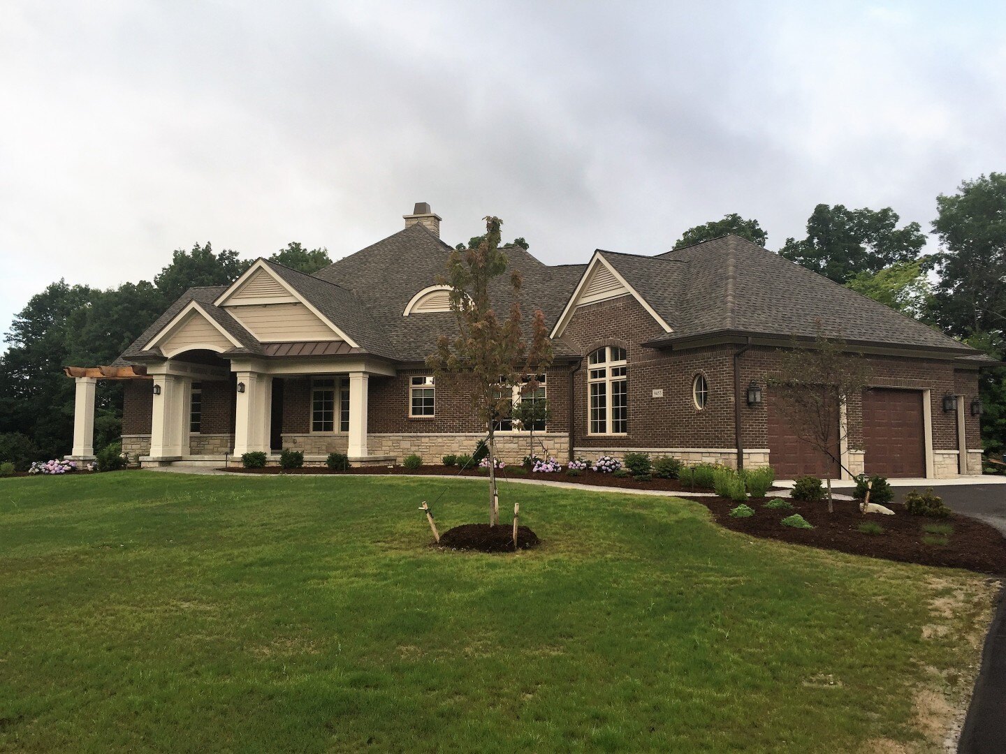 new custom home in michigan with large two car garage, brown and tan exterior, and large front lawn